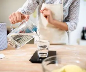 Vue rapprochée d'un chef mesurant le poids d'un verre d'eau dans la cuisine
