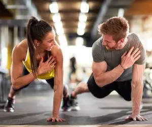 Homme et femme en forme faisant des pompes et s'entraînant à la salle de sport
