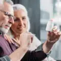 homme âgé et femme regardant une bouteille de pilules à la main