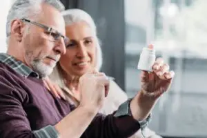 homme âgé et femme regardant une bouteille de pilules à la main