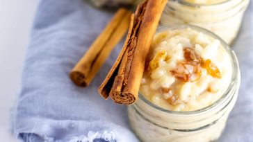 rice pudding in glass jars with cinnamon sticks laid across the top